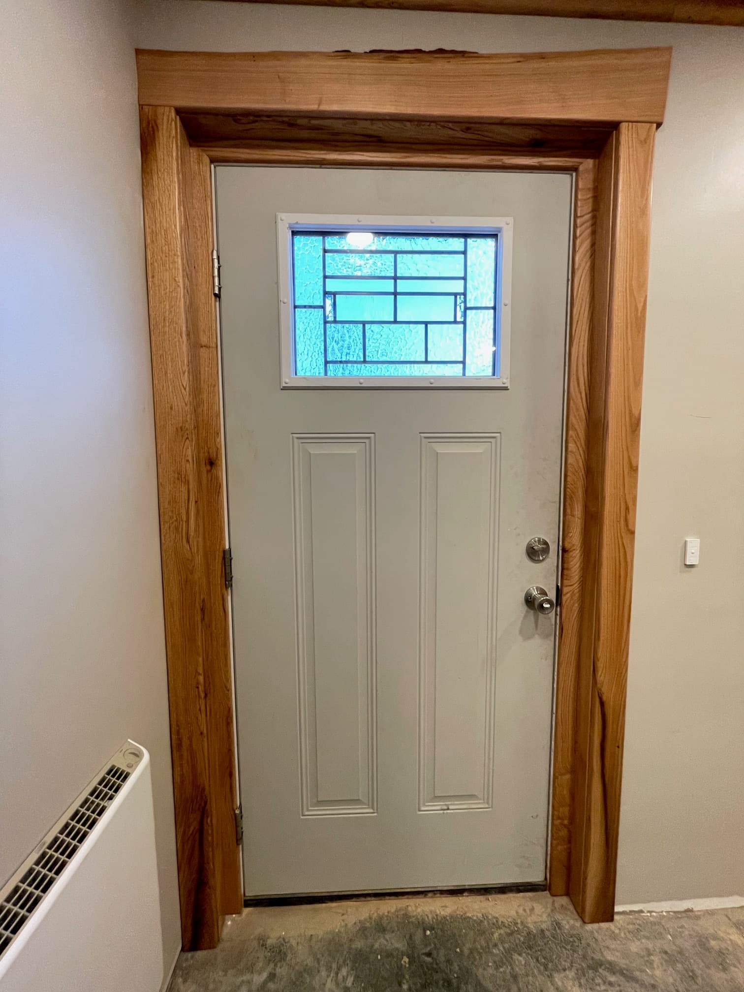 White door with a blue window and thick wood frame, oriented sideways on a wall.