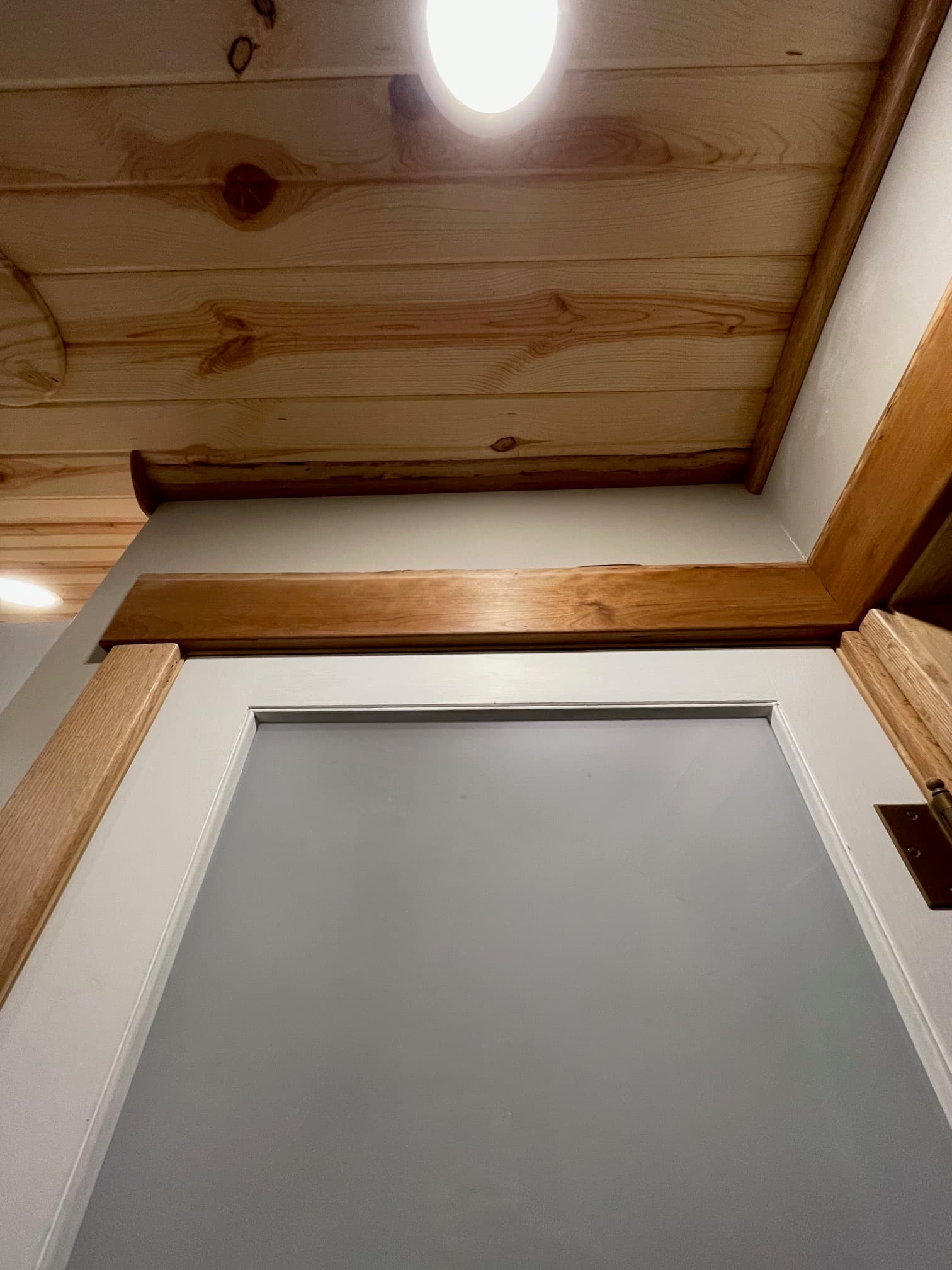 Close-up of knotty pine wall paneling and a white-framed window with natural wood trim.